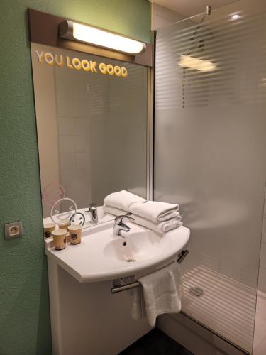 a bathroom with a sink and a shower with a mirror at Premiere Classe Lyon Nord Dardilly in Dardilly