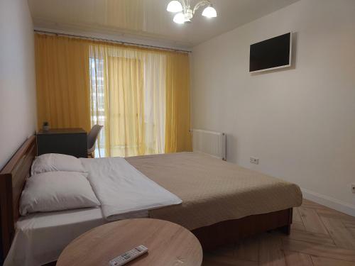 a bedroom with a bed and a table and a television at Апартаменти Класик у ЖК Яровиця in Lutsk