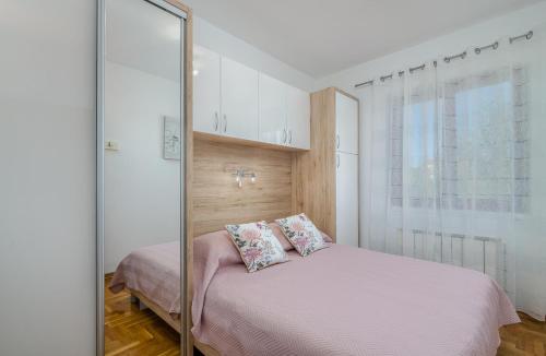 a bedroom with a bed with pink sheets and a mirror at Marina Porat in Porat