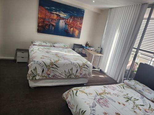 a bedroom with two beds and a painting on the wall at Parramatta Shared Apartment in Sydney