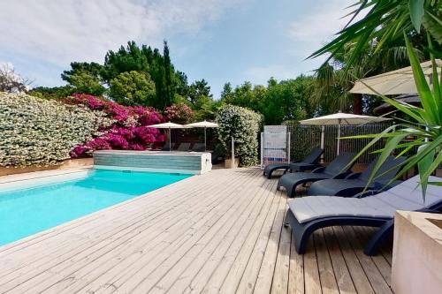 einen Pool mit Stühlen und Sonnenschirmen auf einer Holzterrasse in der Unterkunft Villas CALA CORSA - 3 et 4 Chambres - CALA ROSSA Porto-Vecchio - Villas entièrement Climatisées avec Piscine Chauffée partagée et Piscines Privées - Internet gratuit in Porto-Vecchio