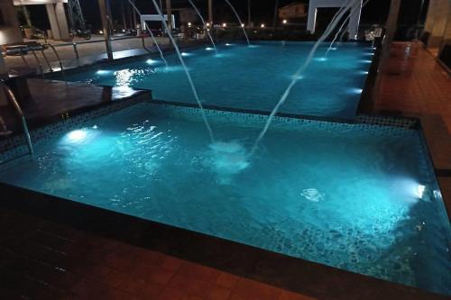 una piscina con dos fuentes en un edificio por la noche en Hotel Adithya View en Dharmastala