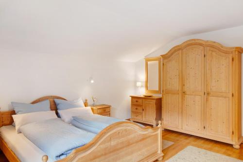 a bedroom with a large bed and a wooden cabinet at Ferienwohnung Zugspitznest in Grainau