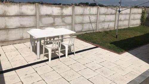 una mesa blanca y 2 sillas en el patio en L’apparté, meublé de tourisme en Saint-Folquin