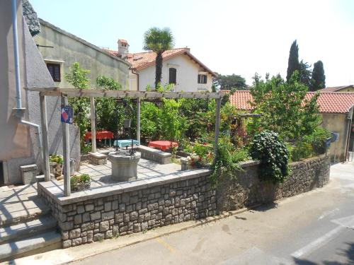 an outdoor garden with a stone wall and a fence at Guesthouse Kuća na šterne in Lovran