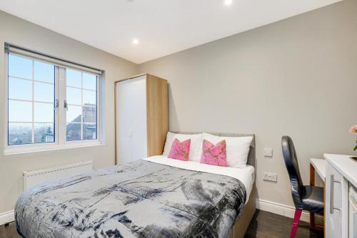 a bedroom with a bed with pink pillows and a window at Cosy studio flat (Finchley Rd) in London