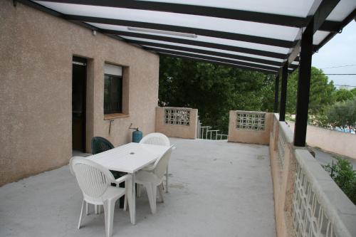 une table blanche et des chaises sur une terrasse dans l'établissement la mer et le soleil, au Grau-dʼAgde