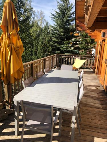 une table et des chaises blanches sur une terrasse en bois dans l'établissement Chalet Le Lauzet, à Les Deux Alpes