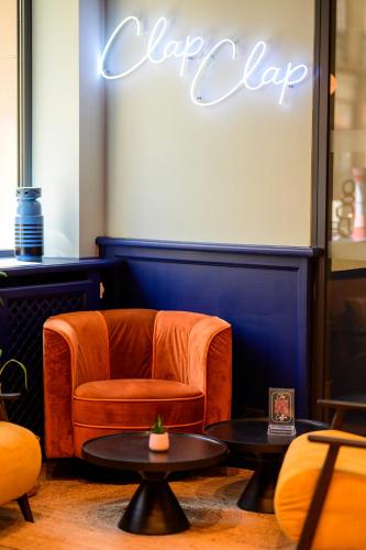 a chair and tables in a room with a sign at ClapClap Hôtel, Food & Bar in Strasbourg