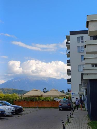 a parking lot with buildings and a mountain in the background at Apartament Ramonte in Zărneşti