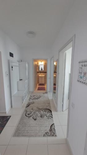 a white room with a hallway with a rug at Apartament Ramonte in Zărneşti