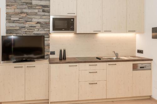 a kitchen with white cabinets and a sink and a microwave at Aparthotel Familiaris - Family Apartments - Pools & Spa in Dolomites in Valdaora