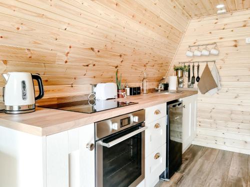 a kitchen in a tiny house with wooden walls at Bective Mill Glamping & Camping in Bective