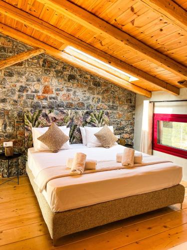 a large bed in a room with a brick wall at Modern Stone Villas with Swimming Pool in Aliveri