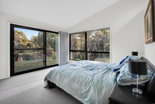 a bedroom with a bed and large windows at Quamby Bluff Lake House, Deloraine, Tasmania in Golden Valley