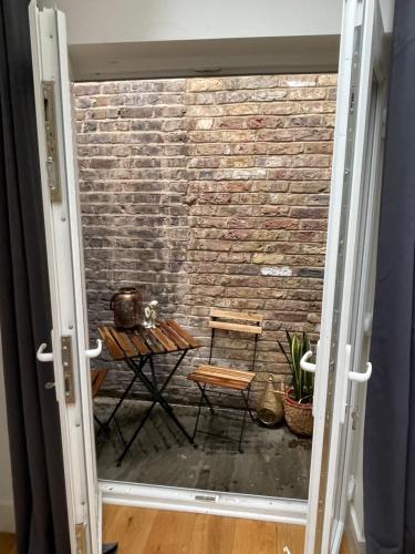 una porta che conduce a un muro di mattoni con tavolo e sedie di Notting Hill Studio Room a Londra