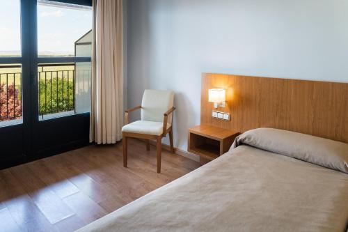 a bedroom with a bed and a chair and a window at AS Monreal del Campo in Monreal del Campo