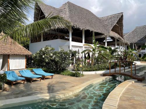 a resort with a swimming pool in front of a building at Paka House-Rafiki Village in Watamu
