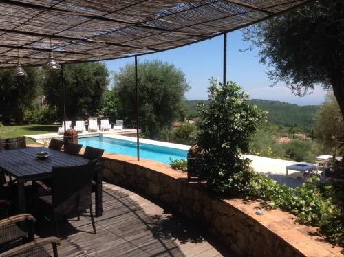 um pátio com uma mesa e uma piscina em Provencal stone farmhouse with sea view, swimming pool and spa em Tourrettes-sur-Loup