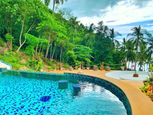 a swimming pool in a resort with trees in the background at Sea View - Palm Villa in Haad Yao