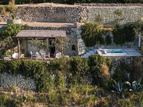 a stone house with a swimming pool and a stone wall at Costa Del Capitano Seaside Villas in Ischia
