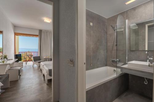 une salle de bain avec une baignoire, un lavabo et une douche dans l'établissement Skiathos Palace Hotel, à Koukounaries
