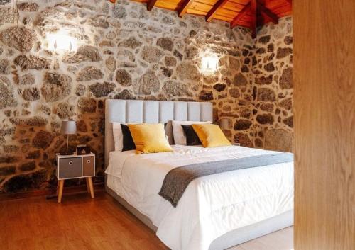 1 dormitorio con 1 cama grande en una pared de piedra en Casa Eido Do Sorro, en Beiral do Lima