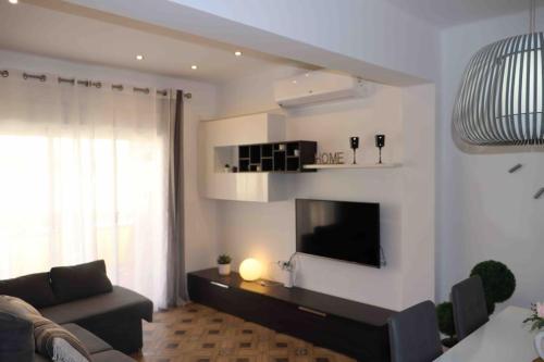 sala de estar con sofá y TV de pantalla plana en Precioso apartamento con vistas al mar. Piscina. en Valencia