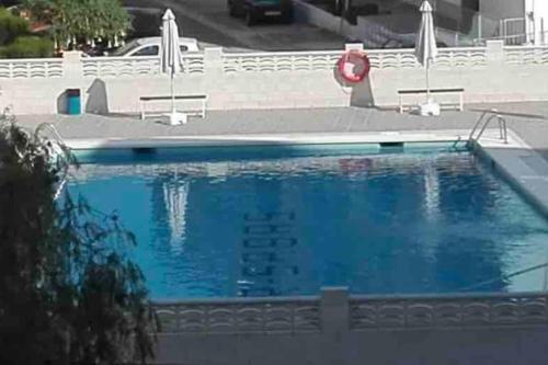 ein großer blauer Pool mit einem roten Rettungsschwimmer in der Unterkunft Precioso apartamento con vistas al mar. Piscina. in Valencia