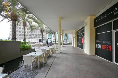 a restaurant with tables and chairs and palm trees at Al Reems Retreat Victorian 1BR Apartment in Abu Dhabi