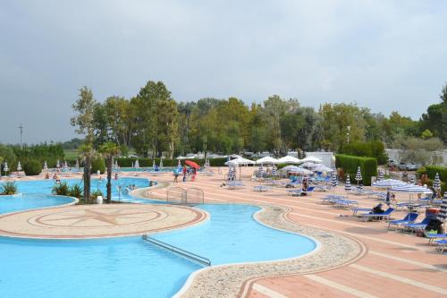 una grande piscina con sedie e persone in un resort di Albatross Mobile Homes on Camping Laguna Village a Porto Falconera