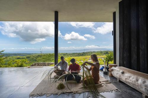 a group of people sitting on the porch of a house at MAUA Nusa Penida Bali in Nusa Penida