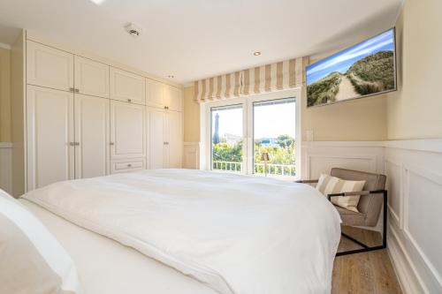 a white bedroom with a large bed and a window at App Kampen in Kampen