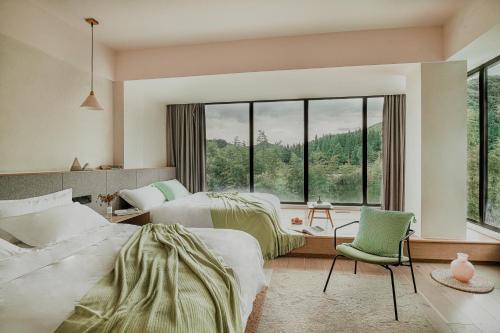 1 dormitorio con 2 camas y ventana grande en Creek Moganshan Design B&B en Deqing