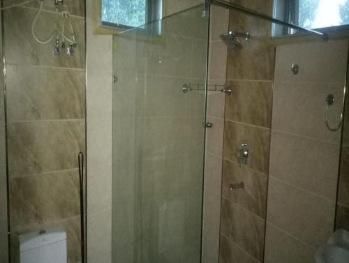 y baño con ducha y puerta de cristal. en StayApart - Aasmaa Farm Stay, en Ābādpura