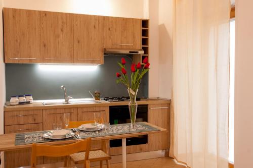 AMORE SE-WOODEN APARTMENTS في كوراتو: مطبخ مع طاولة عليها إناء من الزهور