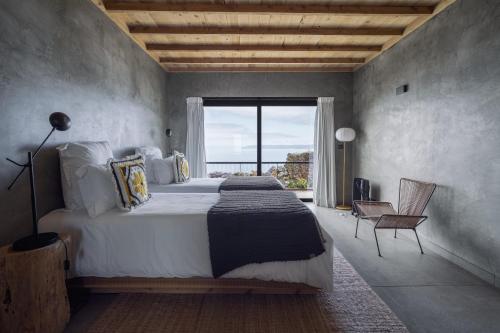 a bedroom with a large bed and a large window at Lava Homes in Santo Amaro