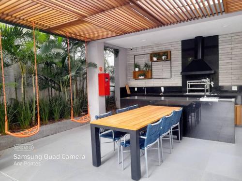 uma cozinha com uma mesa de madeira e cadeiras azuis em Studio charmoso muito bem localizado em São Paulo