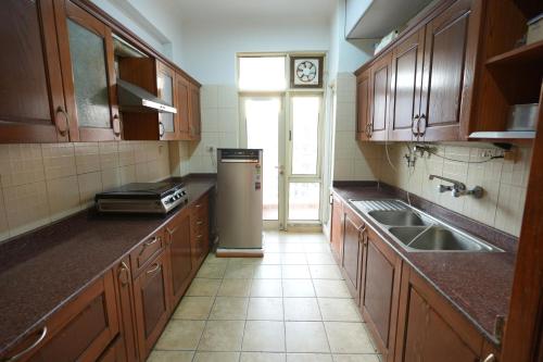 a kitchen with wooden cabinets and a sink and a refrigerator at DESIRE Service Apartments- CyberCity in Gurgaon