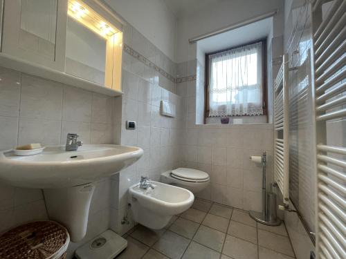 a white bathroom with a sink and a toilet at Appartamenti Casa Albi in Pinzolo