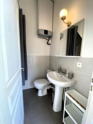 La salle de bains blanche est pourvue de toilettes et d'un lavabo. dans l'établissement Villeurbanne • T1 Février • HostisY, à Villeurbanne