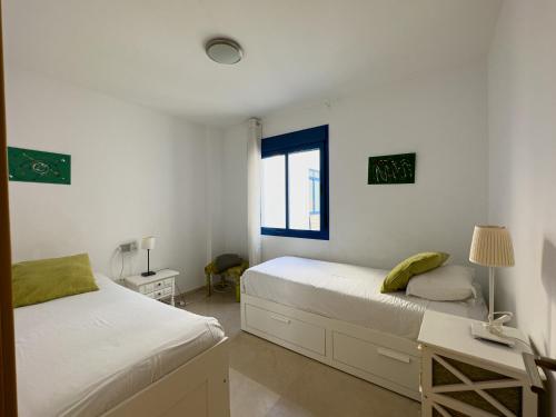 a bedroom with two beds and a desk and a window at Penthouse by the beach in Torrox Costa