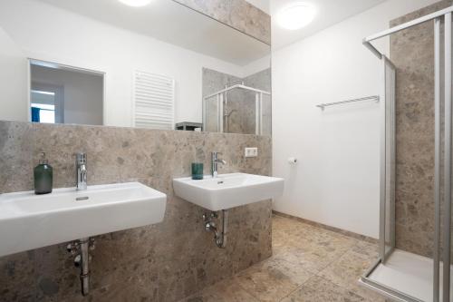 a bathroom with two sinks and a shower at easy flat Villach main plaza in Villach