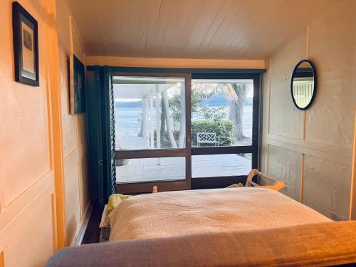 a bedroom with a bed and a large window at Deerubbin Boat House in Dangar Island