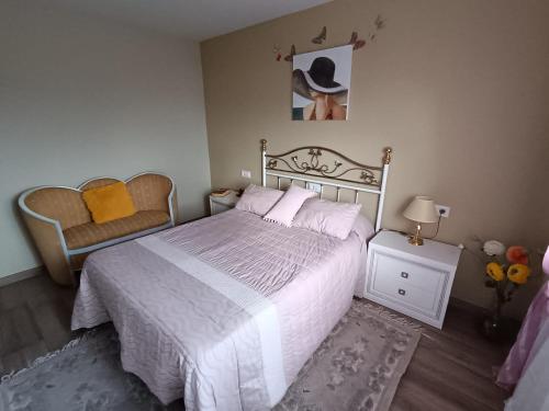 een slaapkamer met een wit bed en een stoel bij A Cavadiña in Vilaboa