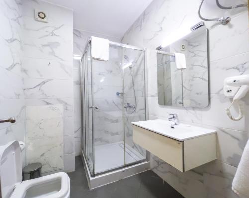 a white bathroom with a shower and a sink at Maroko Bayshore Suites in Lagos