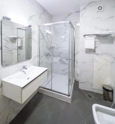 a white bathroom with a shower and a sink at Maroko Bayshore Suites in Lagos
