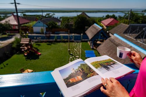 a woman sitting at a table reading a book at Pensiunea Cuplu Călător in Jurilovca