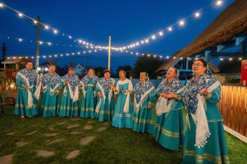 eine Gruppe von Frauen in blauen Kleidern, die unter Lichtern stehen in der Unterkunft Pensiunea Cuplu Călător in Jurilovca