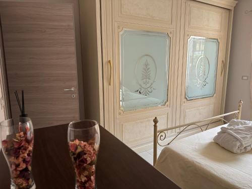 ein Schlafzimmer mit einem Bett und einem Tisch mit zwei Gläsern in der Unterkunft Casa dolce casa in Trecastagni